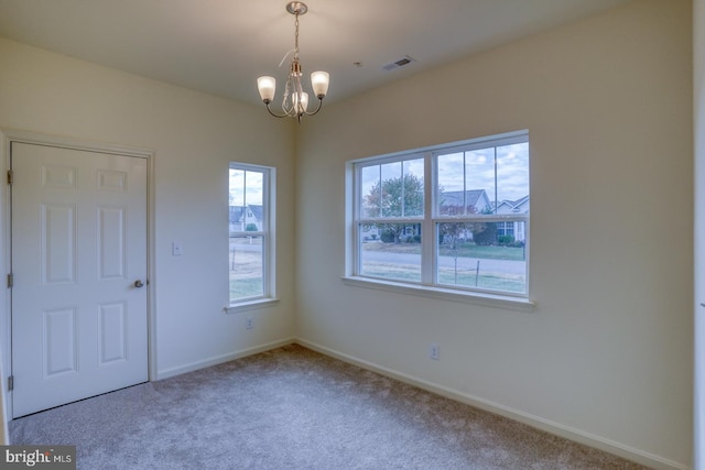 carpeted spare room featuring an inviting chandelier