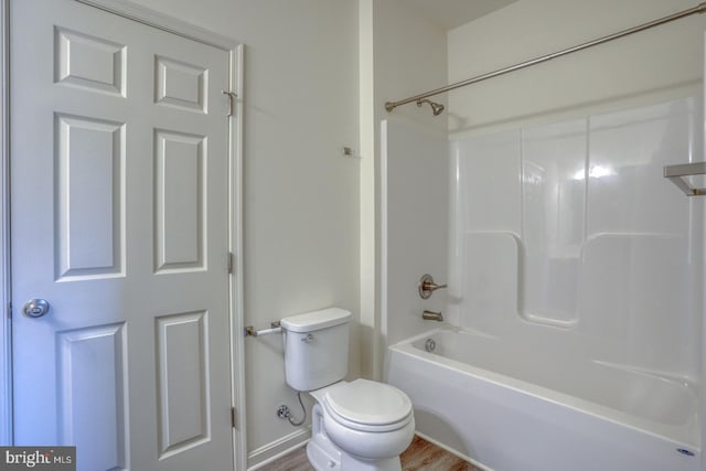 bathroom featuring hardwood / wood-style flooring, shower / washtub combination, and toilet