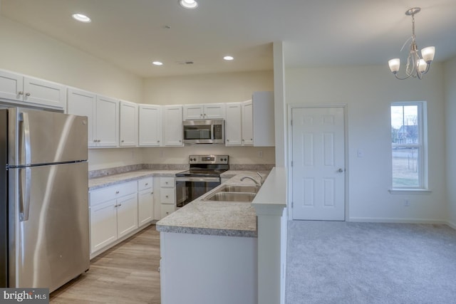 kitchen with white cabinetry, stainless steel appliances, sink, and pendant lighting