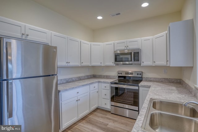 kitchen with white cabinets, sink, light hardwood / wood-style floors, and stainless steel appliances