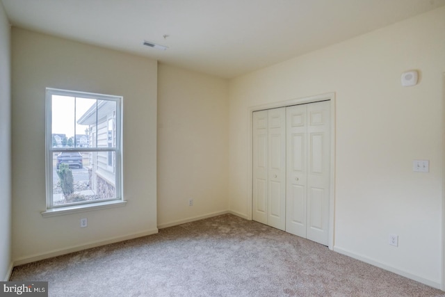 unfurnished bedroom with light carpet and a closet