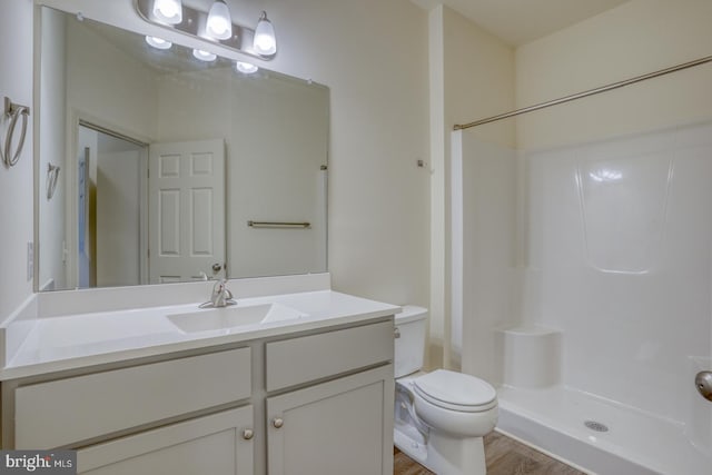 bathroom with hardwood / wood-style flooring, vanity, toilet, and walk in shower