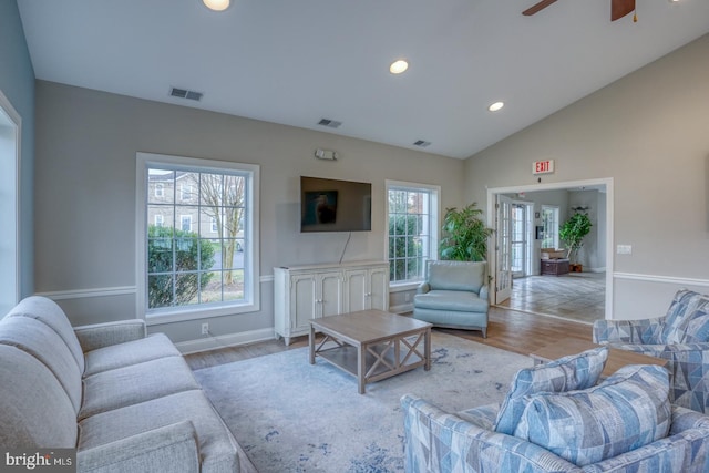 living room with light hardwood / wood-style floors, ceiling fan, plenty of natural light, and vaulted ceiling