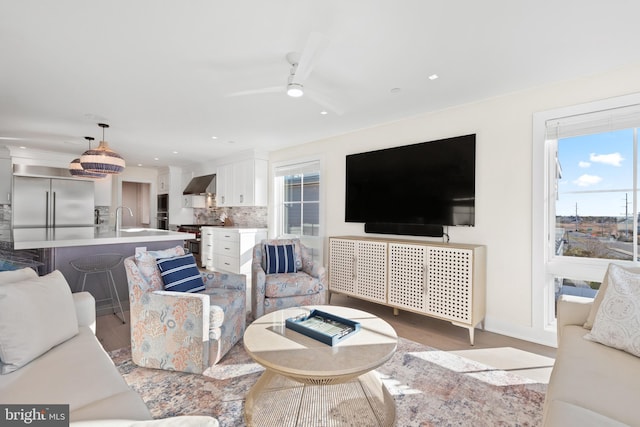 living room with ceiling fan, light wood-type flooring, and sink