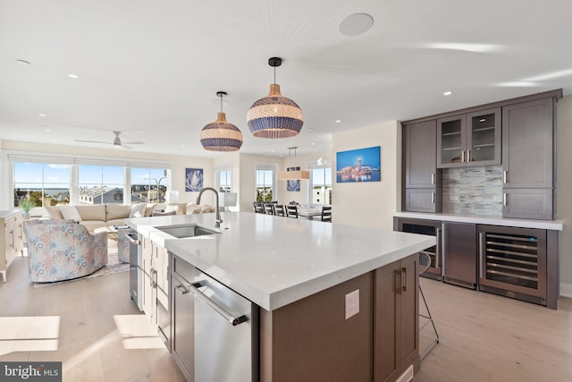 kitchen featuring plenty of natural light, light hardwood / wood-style floors, dark brown cabinets, and decorative light fixtures