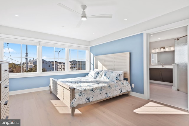 bedroom featuring ceiling fan, light hardwood / wood-style flooring, ensuite bathroom, and sink