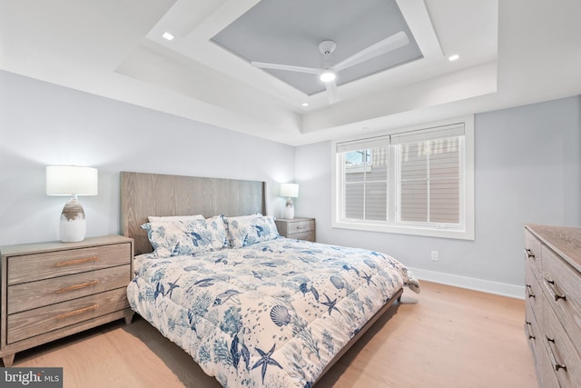 bedroom with a tray ceiling and light hardwood / wood-style floors