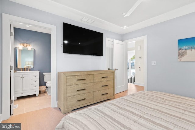 bedroom featuring ensuite bathroom and light hardwood / wood-style flooring