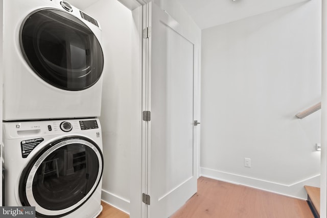 laundry room featuring light hardwood / wood-style floors and stacked washer / drying machine