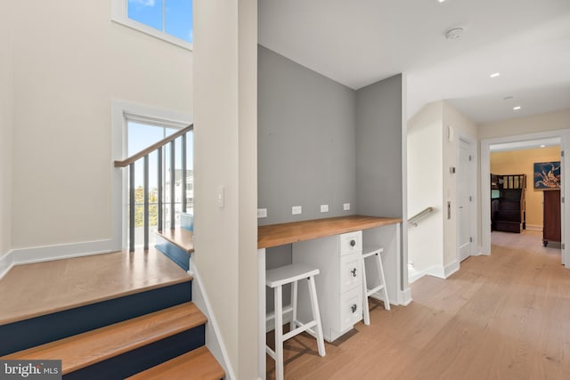 stairway with built in desk and hardwood / wood-style flooring