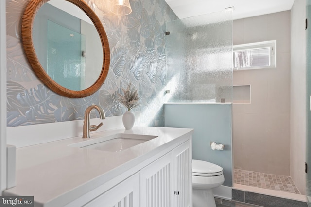 bathroom featuring vanity, toilet, and tiled shower