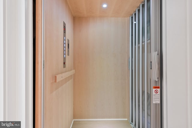 room details with wooden walls, wood-type flooring, and elevator