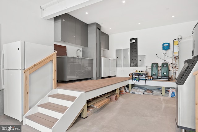 kitchen featuring gray cabinetry, white fridge, washer / dryer, and electric panel