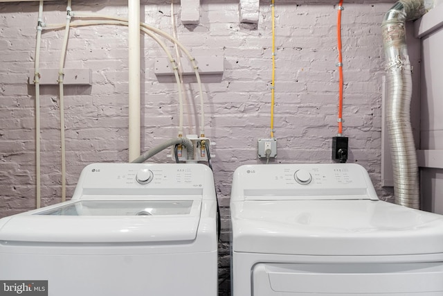 washroom with washer and clothes dryer and brick wall