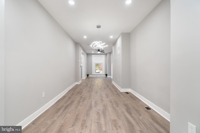 hallway featuring an inviting chandelier and light hardwood / wood-style floors