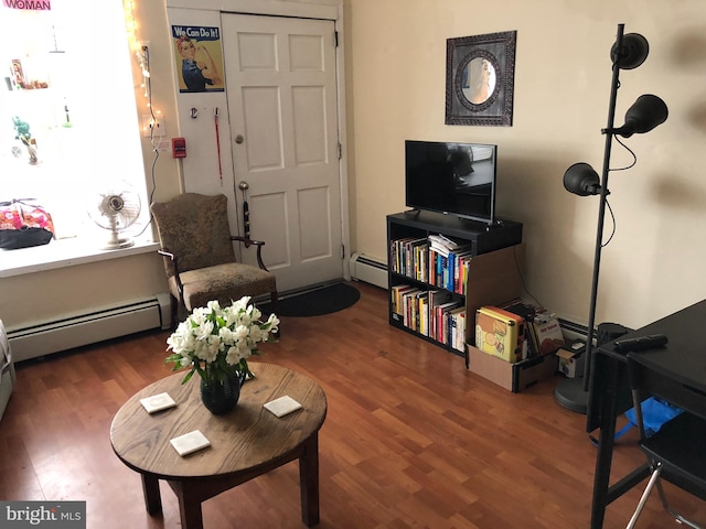 sitting room with a baseboard heating unit and dark wood-type flooring