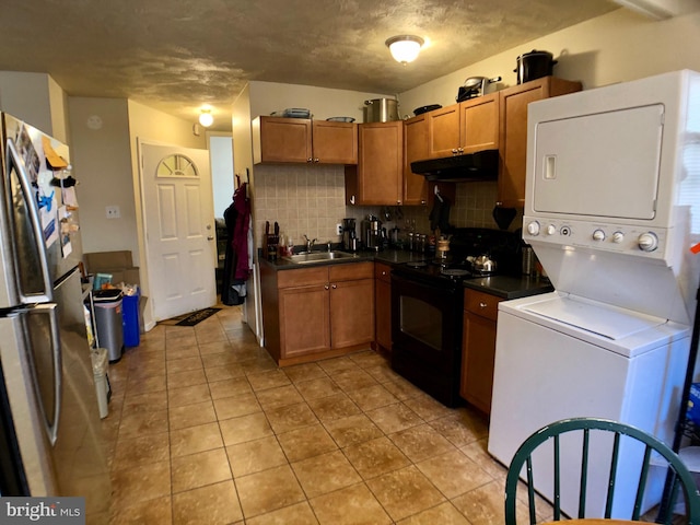 kitchen featuring sink, black electric range, stainless steel fridge, stacked washing maching and dryer, and tasteful backsplash