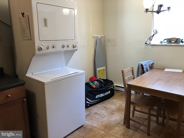 clothes washing area with stacked washer / drying machine, cabinets, light tile patterned floors, and an inviting chandelier