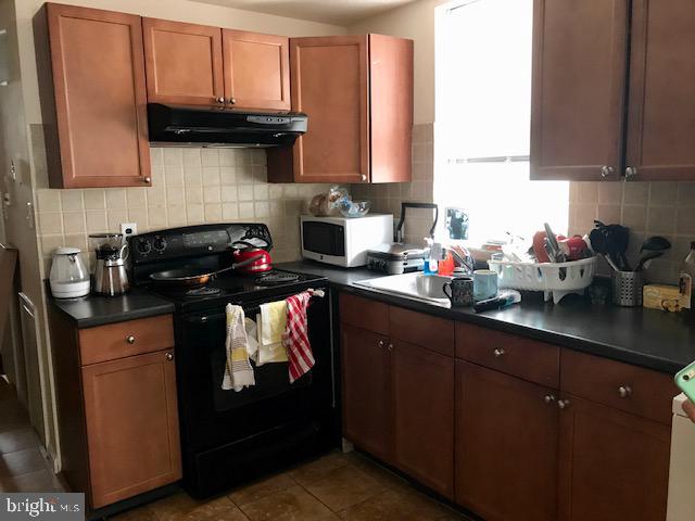 kitchen featuring tile patterned floors, decorative backsplash, and black range with electric stovetop