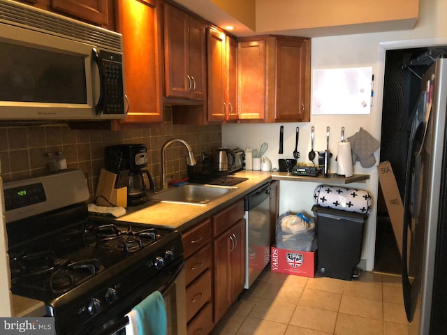 kitchen with backsplash, light tile patterned floors, sink, and appliances with stainless steel finishes