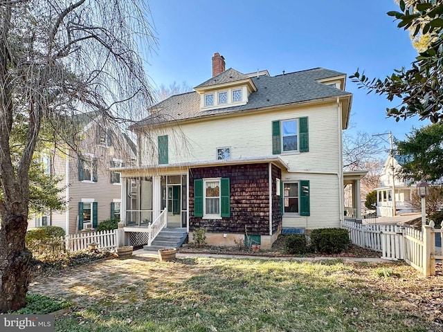 view of front of home featuring a front lawn, fence, a sunroom, and a chimney