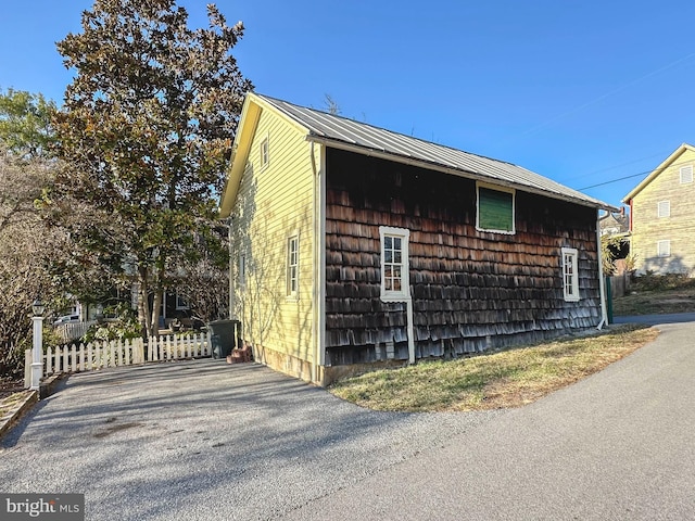 view of side of property with fence and metal roof