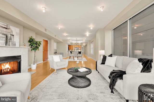 living room with light wood-type flooring and an inviting chandelier