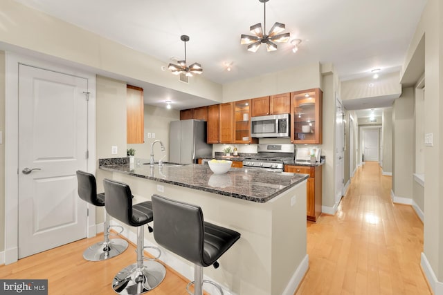 kitchen featuring a kitchen bar, stainless steel appliances, light hardwood / wood-style floors, kitchen peninsula, and a chandelier