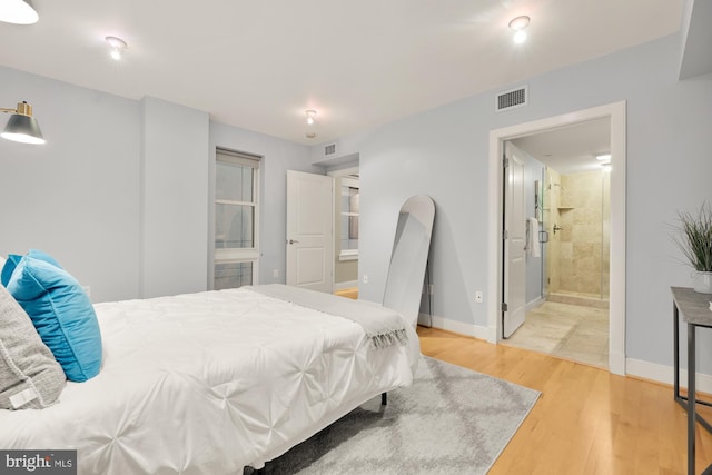 bedroom with hardwood / wood-style floors and ensuite bath