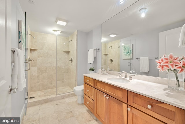 bathroom featuring toilet, vanity, and a shower with shower door