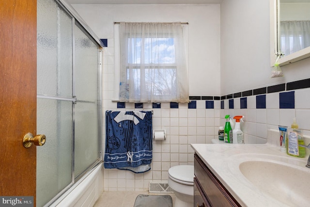 full bathroom with enclosed tub / shower combo, toilet, tile walls, tile patterned flooring, and vanity