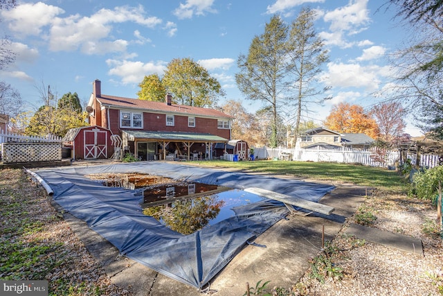 rear view of house featuring a shed and a covered pool