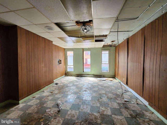 empty room with a drop ceiling and wooden walls