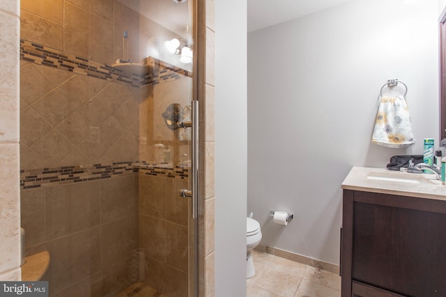 bathroom featuring tile patterned floors, vanity, a shower with shower door, and toilet