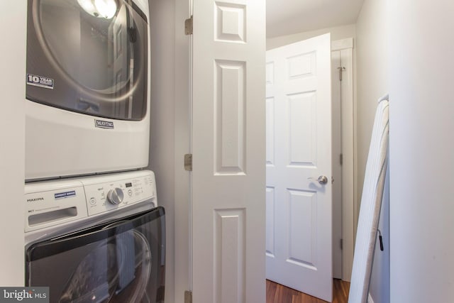 laundry room featuring dark hardwood / wood-style flooring and stacked washer / drying machine