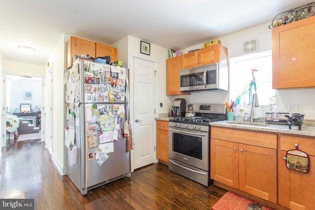 kitchen with light stone countertops, stainless steel appliances, dark hardwood / wood-style floors, and sink