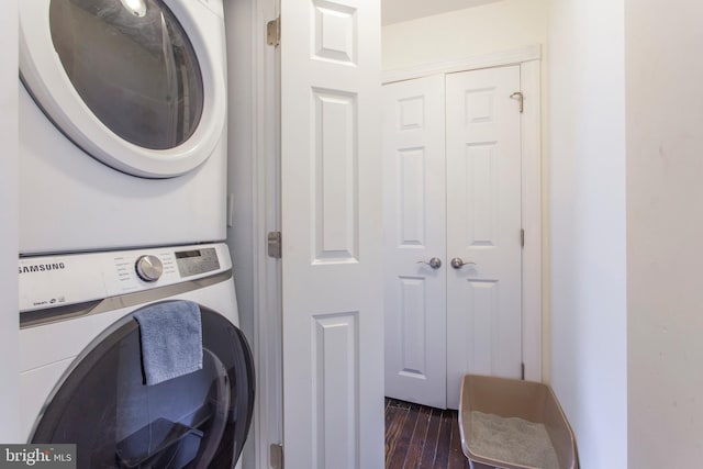 washroom with stacked washing maching and dryer and dark hardwood / wood-style floors