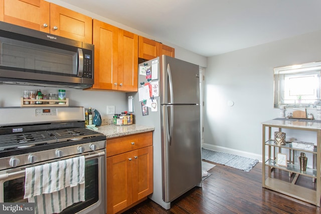 kitchen featuring light stone countertops, stainless steel appliances, and dark hardwood / wood-style floors