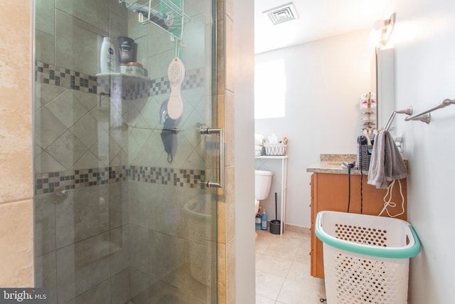 bathroom featuring tile patterned flooring, vanity, toilet, and a shower with door