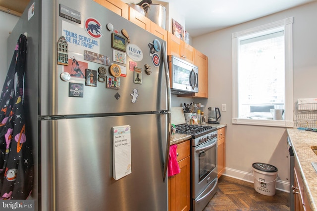 kitchen featuring dark parquet flooring, stainless steel appliances, and light stone counters