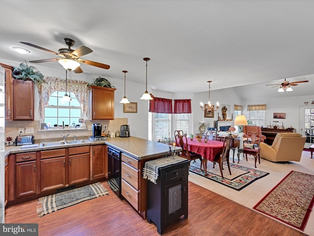 kitchen with kitchen peninsula, plenty of natural light, decorative light fixtures, and light wood-type flooring