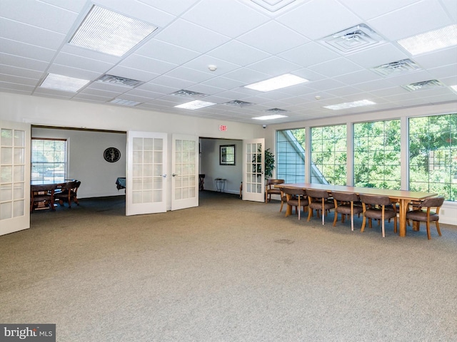 interior space featuring a drop ceiling, a wealth of natural light, and french doors