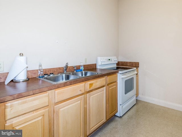 kitchen with light brown cabinetry, sink, and electric range