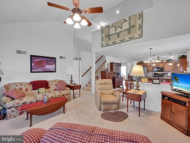 carpeted living room featuring ceiling fan with notable chandelier and lofted ceiling