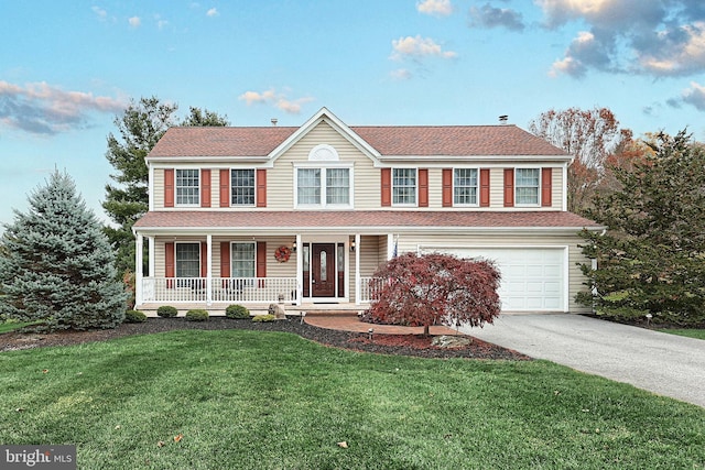 colonial inspired home featuring a porch, a garage, and a front yard