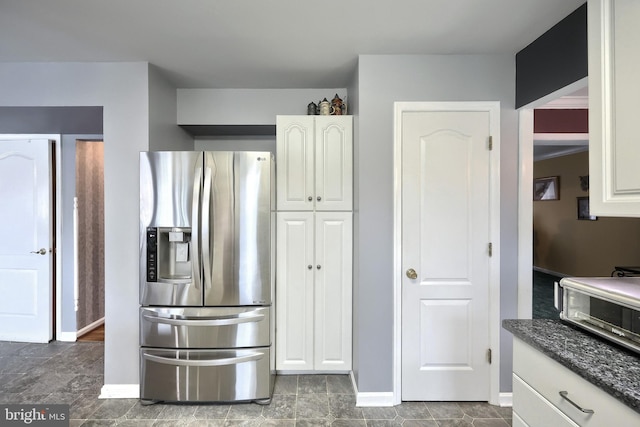 kitchen featuring white cabinets, dark stone countertops, and stainless steel refrigerator with ice dispenser