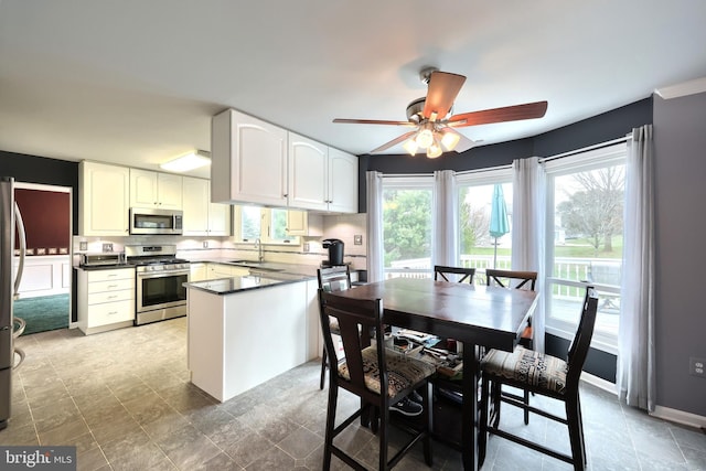 kitchen featuring ceiling fan, sink, kitchen peninsula, white cabinets, and appliances with stainless steel finishes