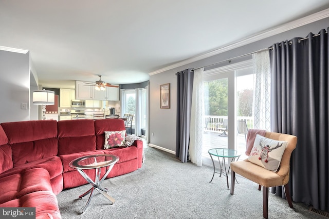 living room featuring ceiling fan, light colored carpet, ornamental molding, and a wealth of natural light