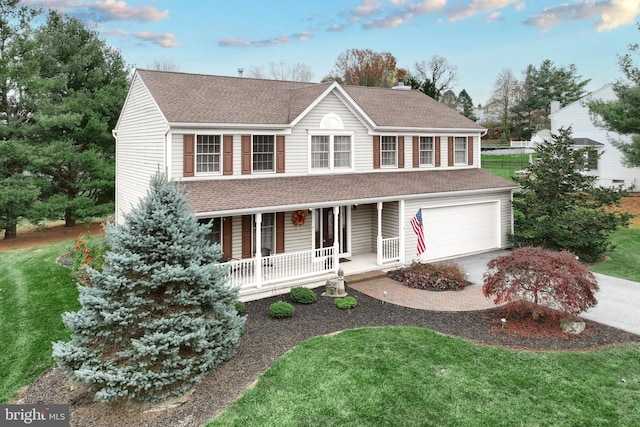 view of front of property with covered porch, a front yard, and a garage