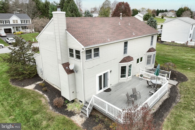 rear view of property featuring a lawn and a deck